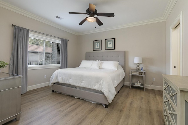 bedroom with light wood finished floors, baseboards, visible vents, and crown molding