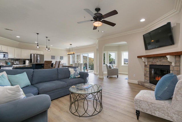 living room with a fireplace, visible vents, baseboards, light wood-style floors, and crown molding