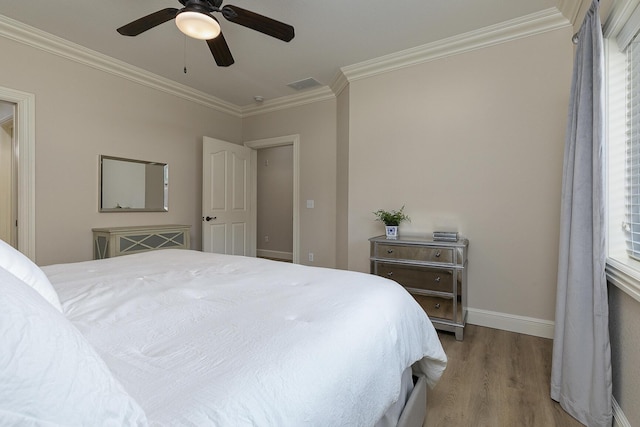 bedroom featuring light wood finished floors, visible vents, ornamental molding, a ceiling fan, and baseboards