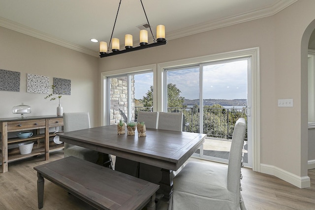 dining space featuring visible vents, arched walkways, light wood-style flooring, ornamental molding, and a chandelier