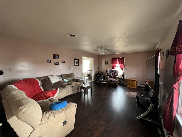 living area with visible vents, dark wood finished floors, a baseboard radiator, ceiling fan, and a textured ceiling