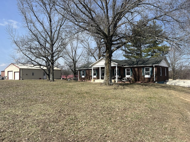 view of front of house featuring brick siding, an outbuilding, covered porch, and a front yard