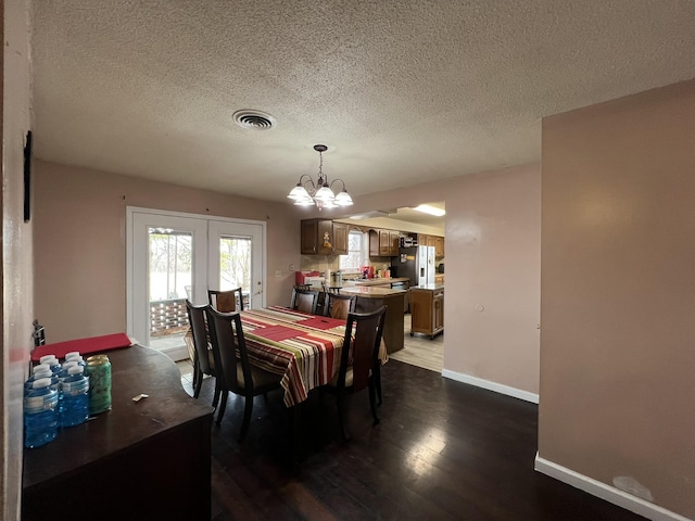 dining room with baseboards, visible vents, dark wood finished floors, a textured ceiling, and a chandelier