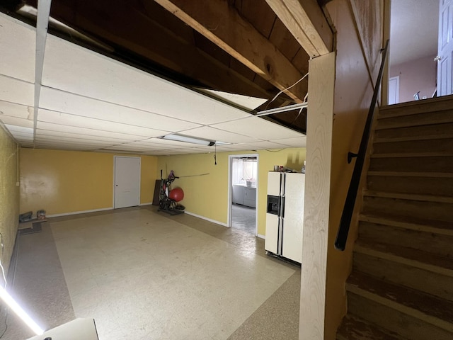 basement featuring white refrigerator with ice dispenser, stairway, baseboards, and tile patterned floors