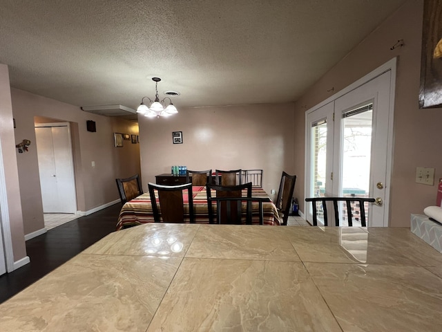 dining space featuring a notable chandelier, a textured ceiling, baseboards, and wood finished floors