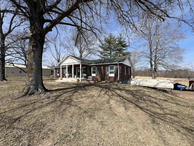 view of front of home with covered porch, brick siding, and driveway