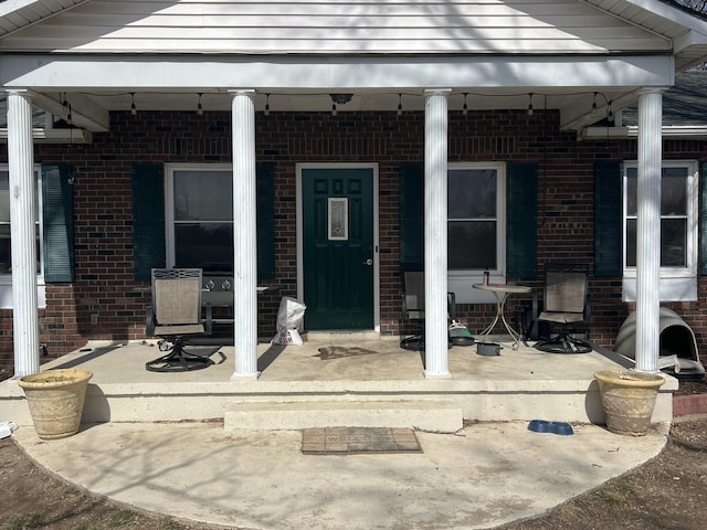 view of exterior entry with covered porch and brick siding