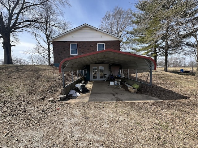 view of front of property with brick siding, dirt driveway, and french doors