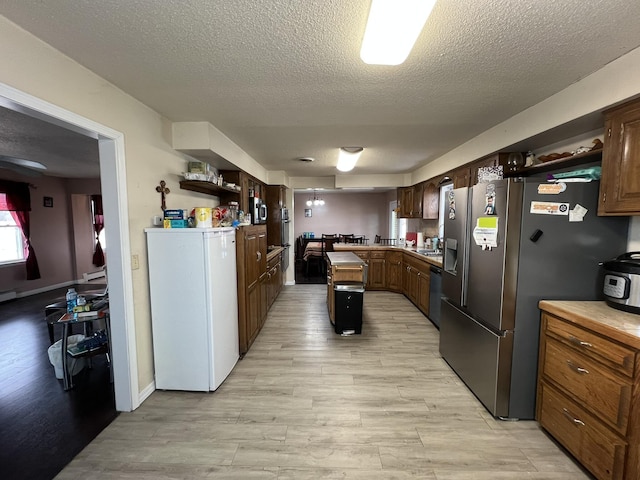 kitchen with dishwashing machine, stainless steel refrigerator with ice dispenser, light countertops, and light wood-style floors