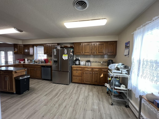 kitchen featuring visible vents, decorative backsplash, light wood-type flooring, stainless steel fridge, and dishwasher