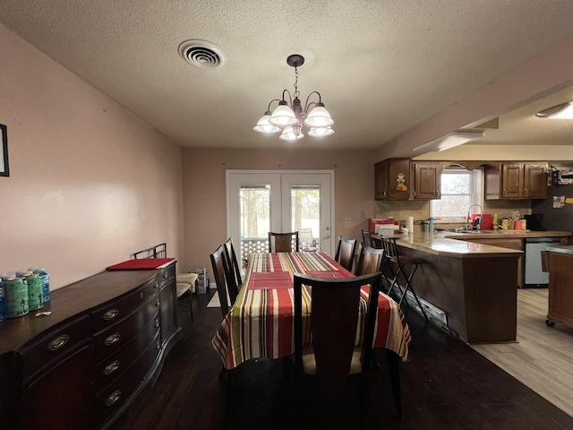 dining space featuring a wealth of natural light, light wood-type flooring, visible vents, and a notable chandelier