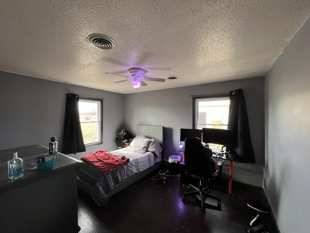 bedroom with a textured ceiling, visible vents, and a ceiling fan