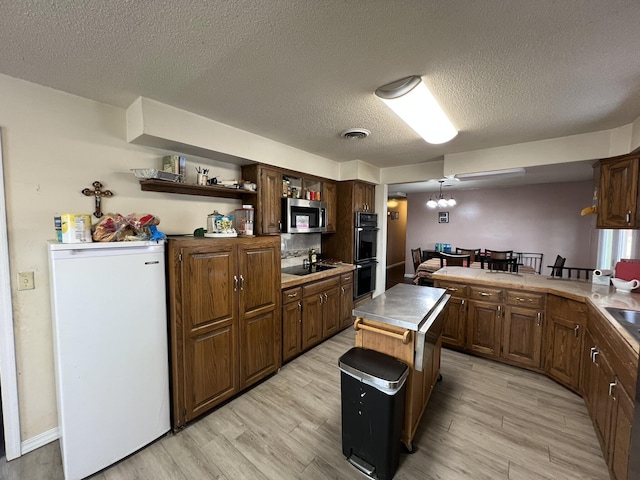 kitchen featuring open shelves, visible vents, light wood-style floors, a peninsula, and black appliances