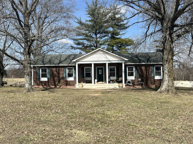 view of front of home featuring a chimney, a front lawn, and brick siding