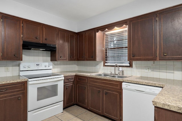 kitchen with white appliances, under cabinet range hood, decorative backsplash, and a sink