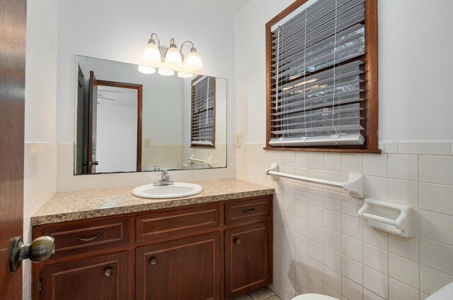 bathroom with wainscoting, vanity, and tile walls