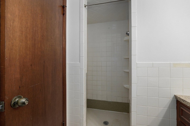 bathroom with vanity, a shower stall, and tile walls