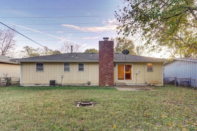 back of house featuring cooling unit, a chimney, fence, and a lawn