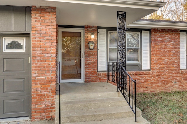 property entrance featuring a garage and brick siding