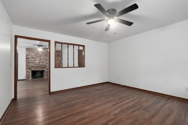 spare room with dark wood finished floors, a fireplace, and baseboards