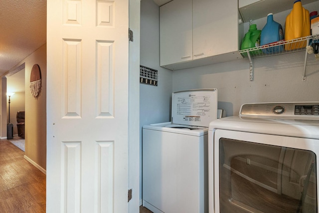 laundry room with washer and dryer, cabinet space, baseboards, and wood finished floors