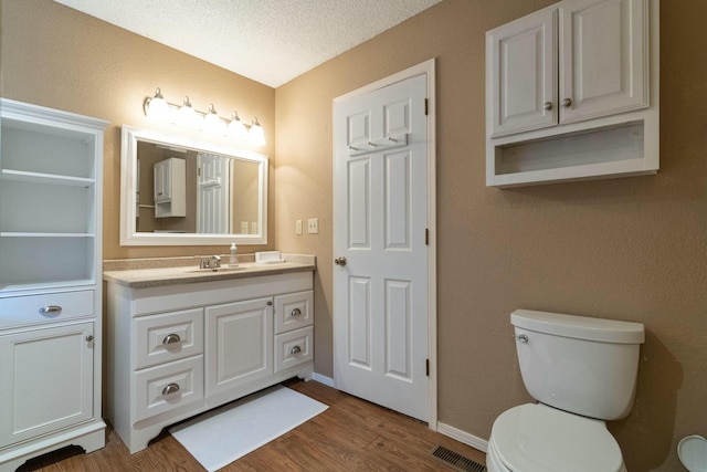 bathroom with visible vents, toilet, wood finished floors, a textured ceiling, and vanity