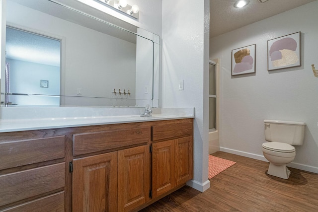 full bath featuring enclosed tub / shower combo, toilet, wood finished floors, vanity, and baseboards