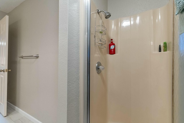 bathroom featuring a stall shower and baseboards