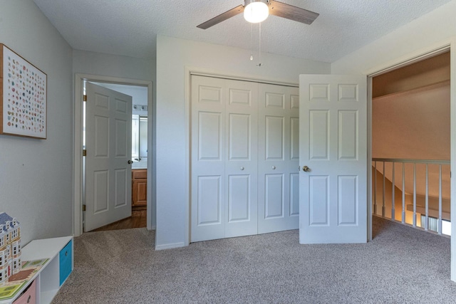 unfurnished bedroom with carpet, a textured ceiling, a ceiling fan, and a closet