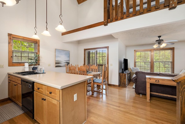 kitchen featuring light wood-style flooring, black dishwasher, a sink, and a peninsula