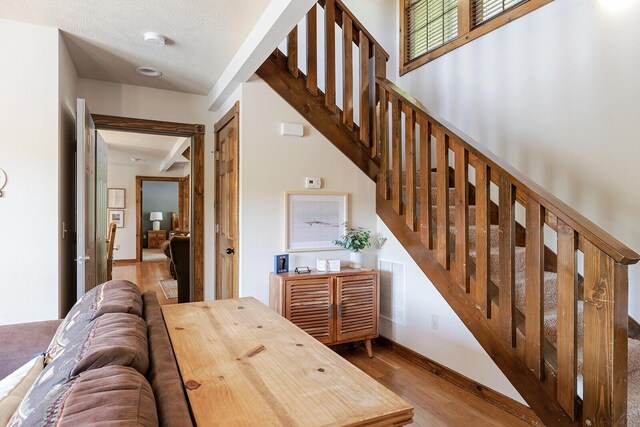 interior space with visible vents, a textured ceiling, baseboards, and wood finished floors