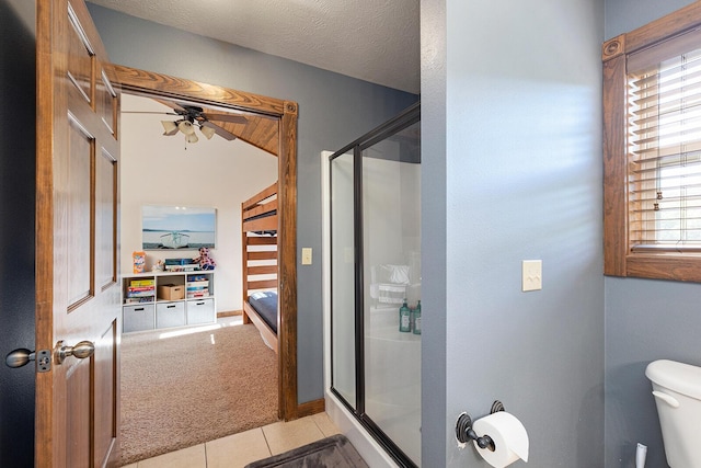 full bath with toilet, a shower stall, ceiling fan, and tile patterned floors