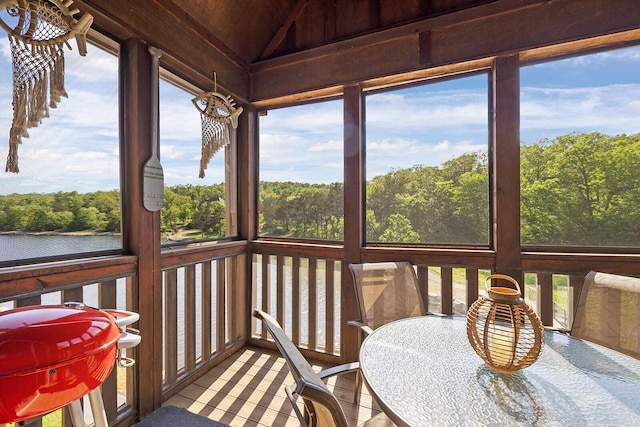 sunroom with a water view, a view of trees, and lofted ceiling