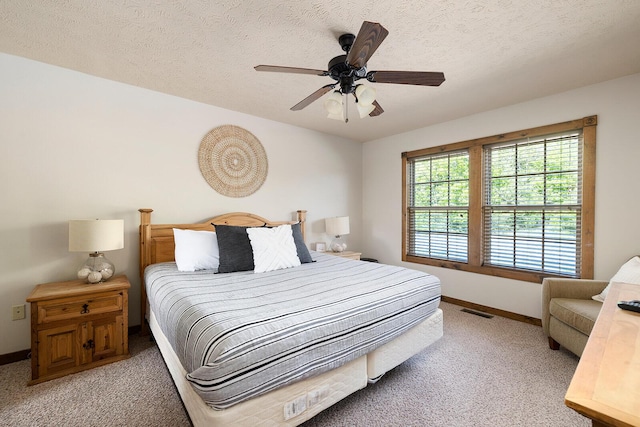 bedroom with light colored carpet, visible vents, a textured ceiling, and baseboards