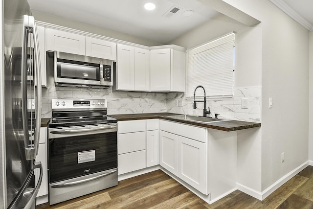 kitchen featuring dark wood-style flooring, tasteful backsplash, visible vents, appliances with stainless steel finishes, and a sink