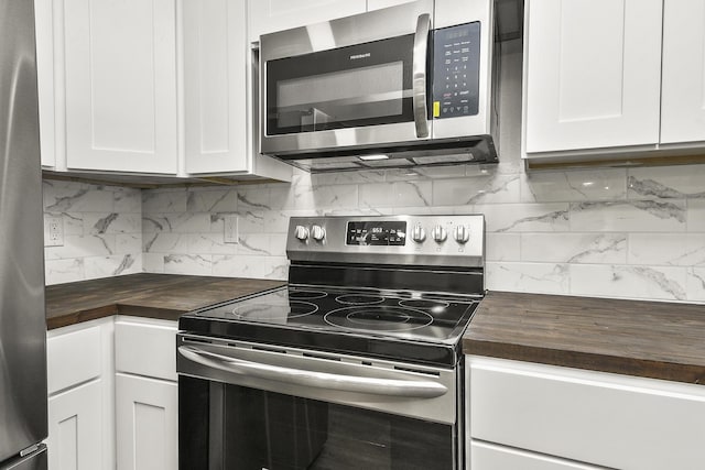 kitchen featuring wooden counters, appliances with stainless steel finishes, backsplash, and white cabinetry