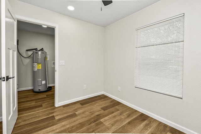 interior space with dark wood-style floors, water heater, baseboards, and a ceiling fan