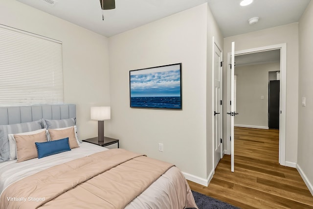 bedroom featuring visible vents, ceiling fan, baseboards, and wood finished floors