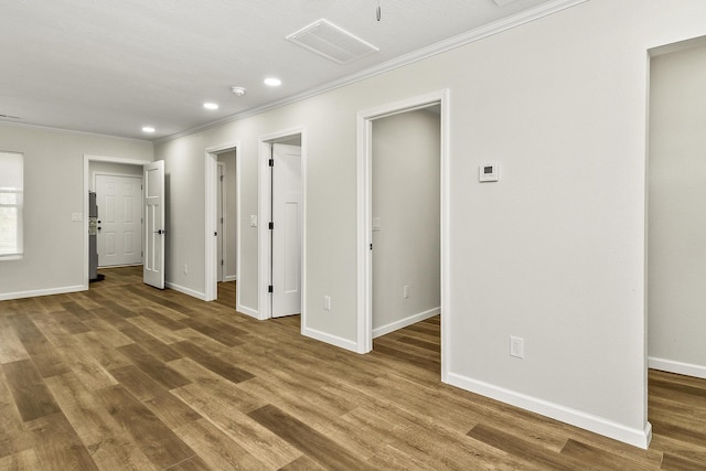 unfurnished bedroom with ornamental molding, wood finished floors, visible vents, and a walk in closet