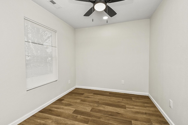 unfurnished room with a ceiling fan, visible vents, dark wood finished floors, and baseboards