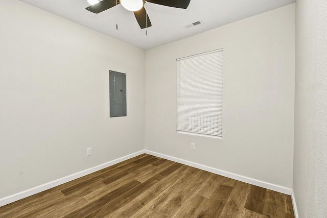 empty room with dark wood-style floors, baseboards, electric panel, and visible vents