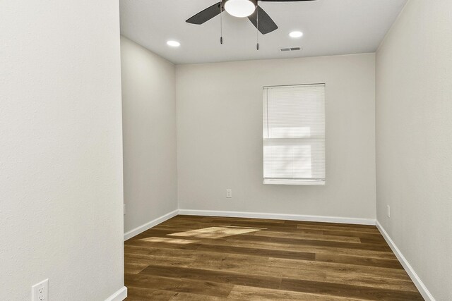 unfurnished room featuring dark wood-type flooring, visible vents, and baseboards