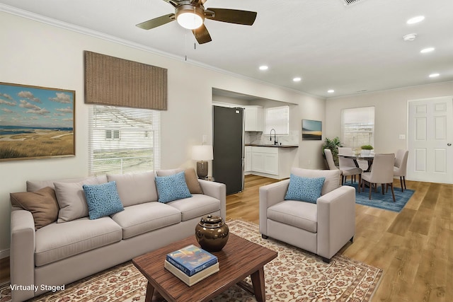 living area featuring light wood-type flooring, ceiling fan, crown molding, and recessed lighting