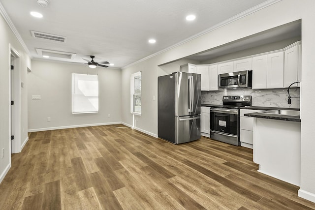 kitchen featuring visible vents, white cabinetry, ornamental molding, appliances with stainless steel finishes, and dark countertops