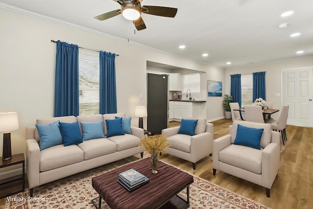 living area with light wood finished floors, ceiling fan, crown molding, and recessed lighting