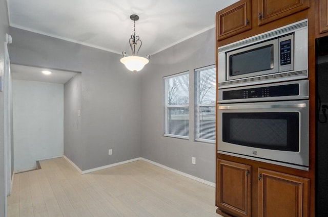 kitchen featuring light wood-style flooring, appliances with stainless steel finishes, brown cabinets, and pendant lighting