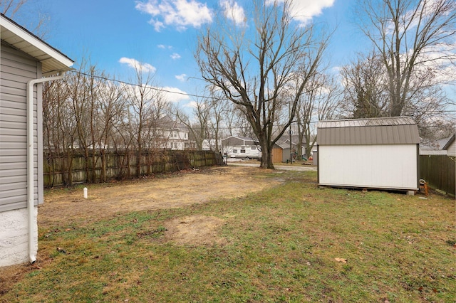 view of yard with a storage shed, fence, and an outbuilding