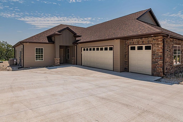 view of front of house featuring cooling unit, a garage, concrete driveway, roof with shingles, and board and batten siding