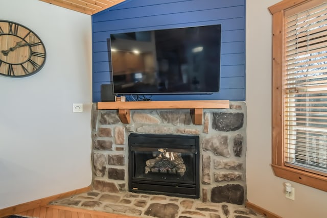 room details featuring a stone fireplace and baseboards