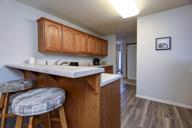 245 Wildflower Rd, Kimberling City, MO 65686 - kitchen with dark wood-style floors, a breakfast bar area, light countertops, brown cabinetry, and a peninsula